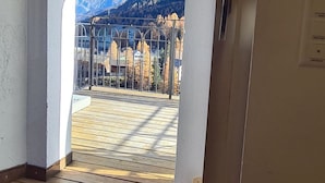 Une vue depuis un balcon doté d’une terrasse en bois, d’une rambarde en métal et d’un ciel dégagé.