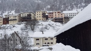Un village de montagne enneigé, avec des bâtiments à plusieurs étages, dont un café appelé « CAFFE GIACOMETTI ».