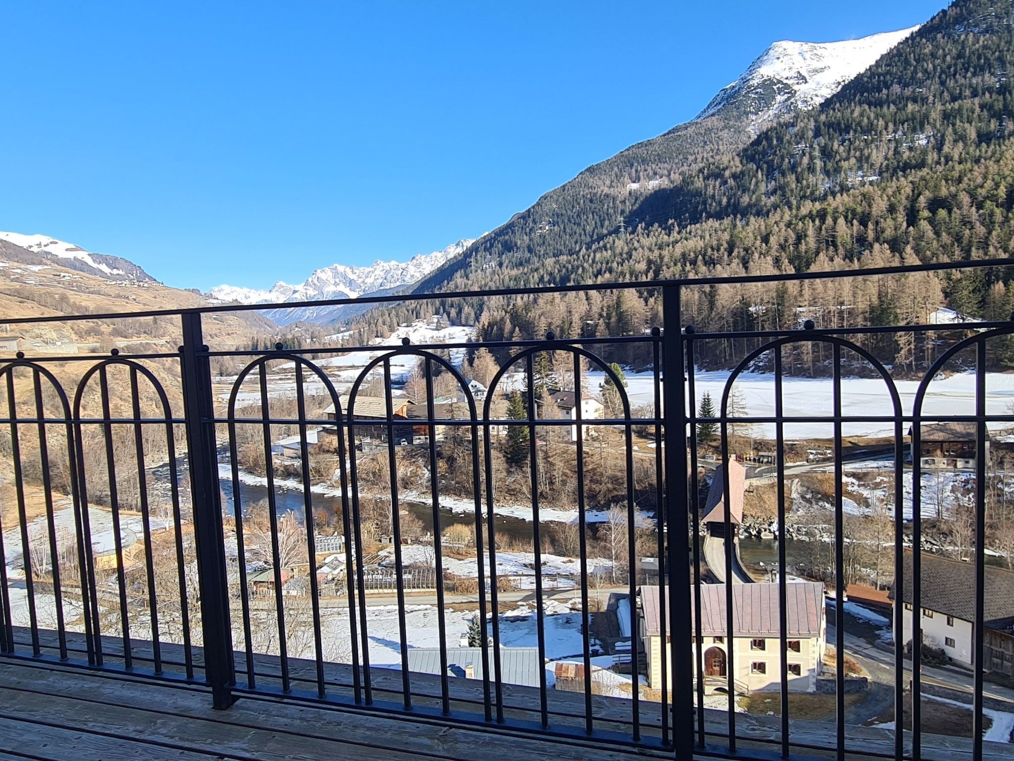 A mountain landscape with a snow-capped peak, a river, and a village with traditional buildings.