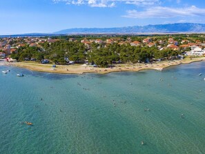 Eine Luftaufnahme einer Küstenstadt mit klarem Wasser, einem Sandstrand und Wohnhäusern.