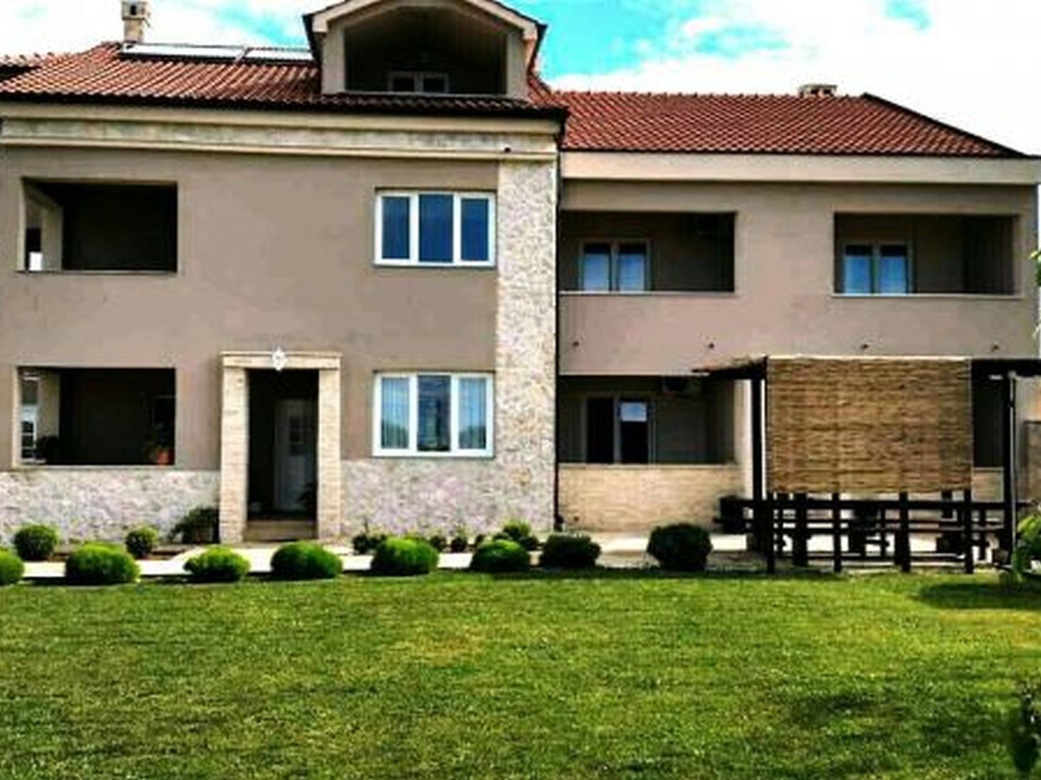 A two-story building with a flat roof, multiple windows, and a well-maintained lawn.