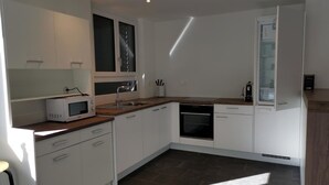 A modern kitchen with white cabinets, a microwave, a sink, and a dishwasher. - HIRSCHEN by Interhome (Gossau SG)