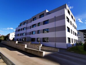 A modern multi-story building with a flat roof, large windows, and a concrete barrier in front. - HIRSCHEN by Interhome (Gossau SG)