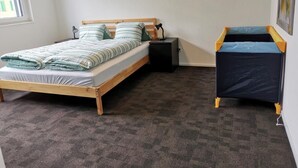 A bedroom with a wooden bed, a nightstand, a small desk, and a storage unit. - HIRSCHEN by Interhome (Gossau SG)