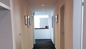 A hallway with carpeted floors, white walls, and doors on both sides leading to a kitchen area in the distance. - HIRSCHEN by Interhome (Gossau SG)
