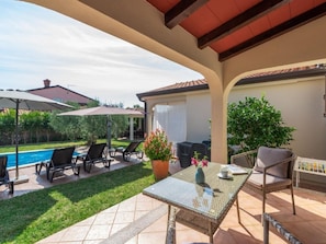 A patio with a pool, lounge chairs, a table with a vase of flowers, and a covered seating area. - Villa Lucas by Interhome (Novigrad (Istra))