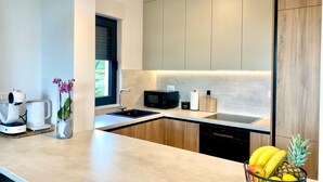 Uma cozinha moderna com lava-louças embutida, micro-ondas e máquina de café.