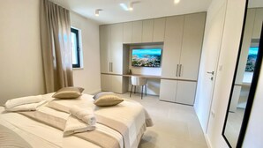 Quarto moderno com uma cama grande, uma escrivaninha e uma televisão.