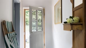 A hallway with a wooden door, a striped cloth hanging, and a tiled floor.
