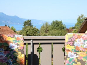 A wooden deck with floral-patterned chairs and a view of a mountainous landscape. - Les Narcisses,Blonay by Interhome (Blonay)