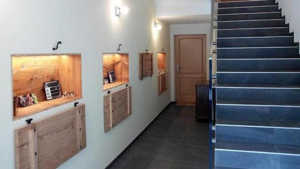 Um corredor com estantes de madeira, escadas e uma porta.
