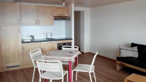 Um espaço compacto com cozinha compacta, uma mesa de jantar com cadeiras e um sofá.
