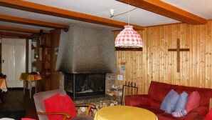 A cozy living room with a fireplace, wooden walls, and a red sofa.
