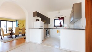 A modern kitchen with white cabinets, a central island, and a dining area with chairs and a table. - Wohnung "Astoria" mit Blick auf das Wasser by Interhome (Zaton)