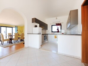 A modern kitchen with white cabinets, a central island, and a dining area with chairs and a table. - Wohnung "Astoria" mit Blick auf das Wasser by Interhome (Zaton)