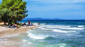 A beach with people sunbathing and swimming, a clear sky, and a calm sea. - Wohnung "Astoria" mit Blick auf das Wasser by Interhome (Zaton)