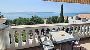 Un balcone con vista sul mare, un tavolo e due sedie.