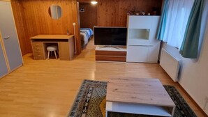 A compact room with a wooden desk, a television, a bed, and a wardrobe. - Chez Rosalie by Interhome (La Roche FR)
