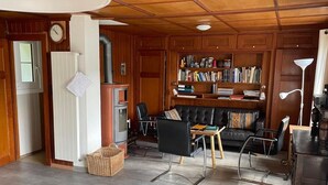 A cozy living room with a fireplace, a bookshelf, and a comfortable seating area. - Chalet Le Clapotis by Interhome (Le Lieu)