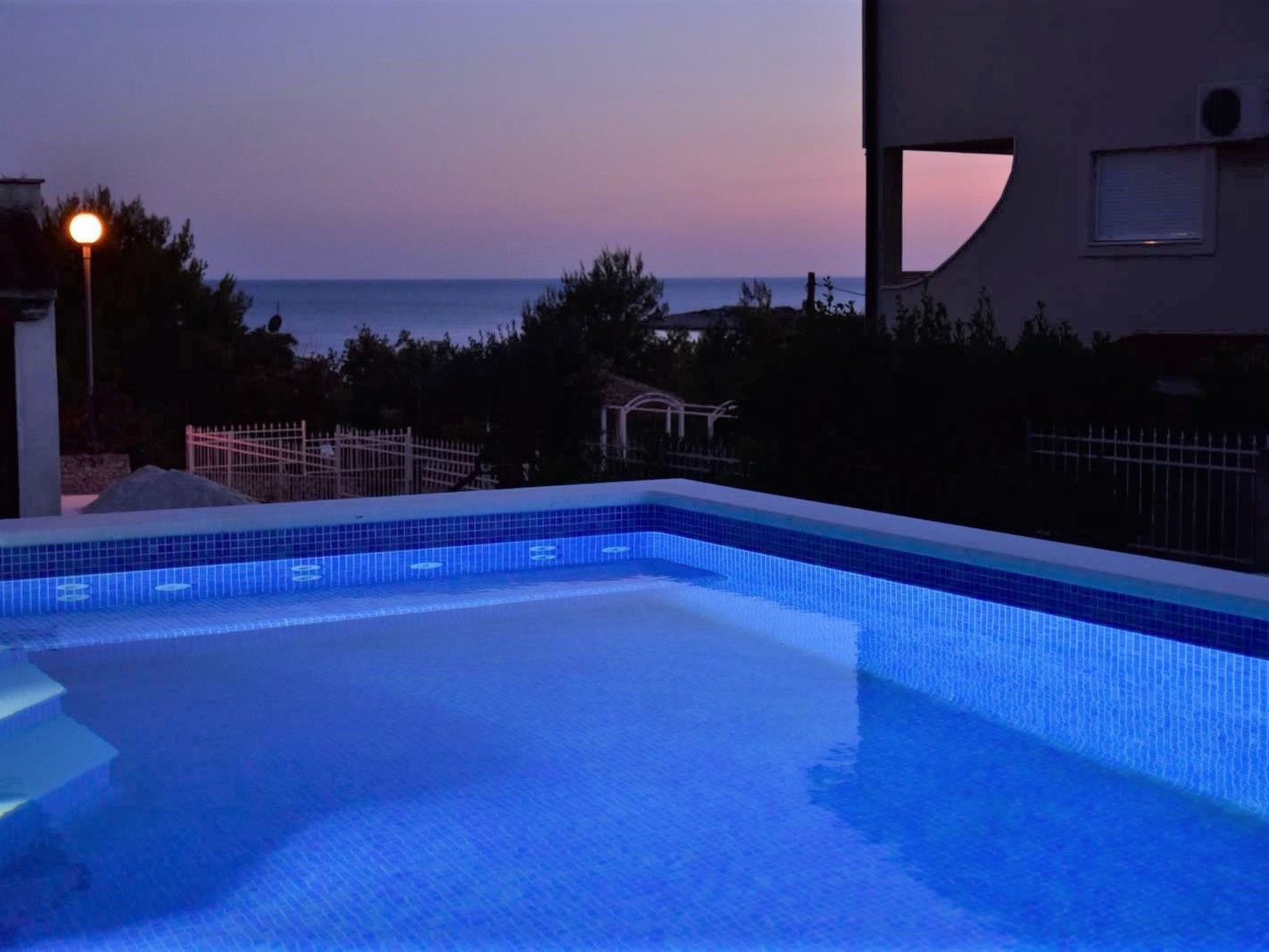 Una piscina con vista al mar al atardecer.