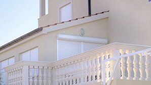 A building with a white balcony with balusters, a white door, and a window with shutters. - Villa Luger EG by Interhome (Rogoznica/Ražanj)