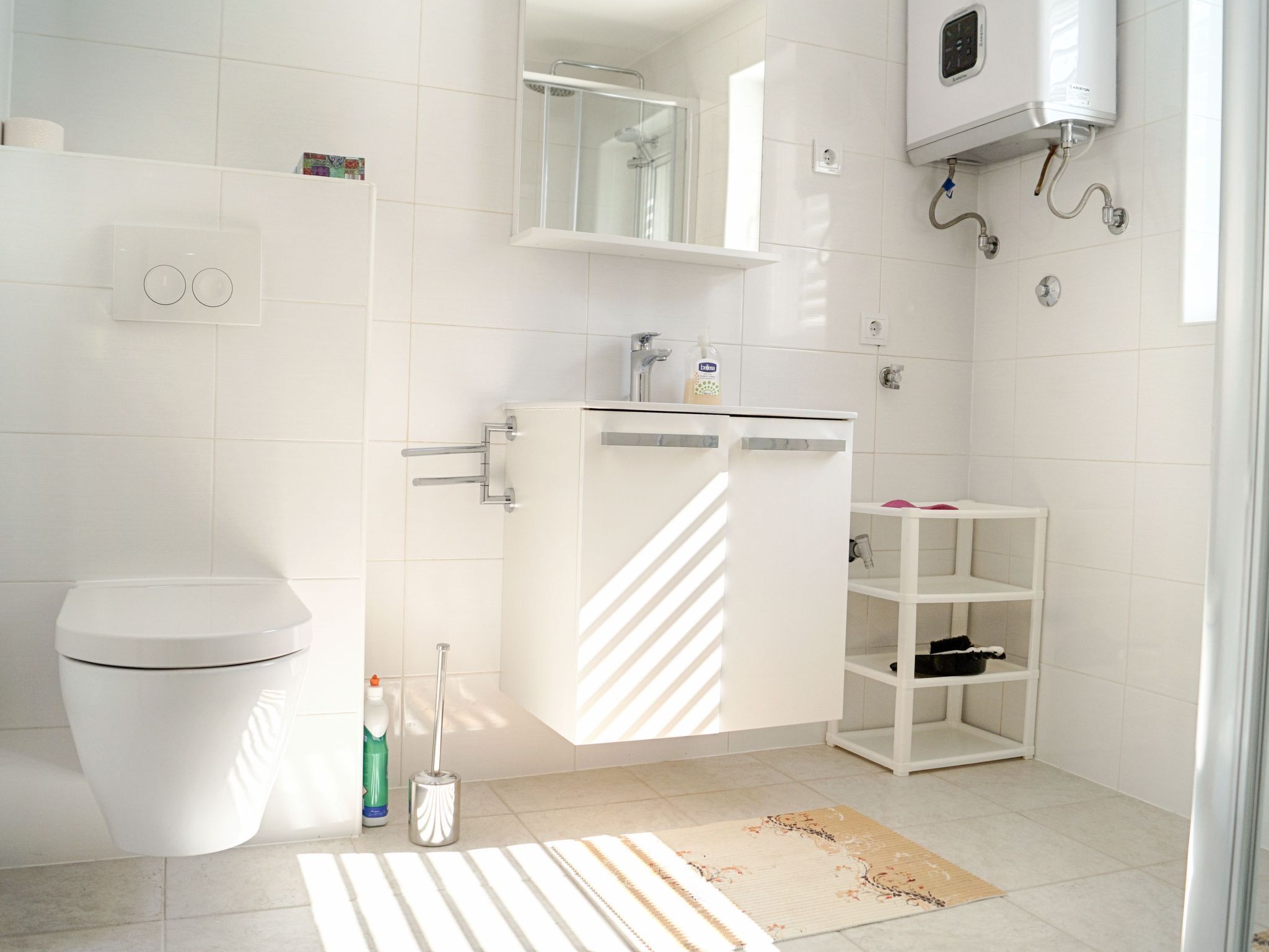 Een moderne badkamer met toilet, een wastafel met spiegel, douche en een ingebouwde verwarming.