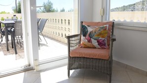 A wicker chair with a cushion and a view of an outdoor patio area with a table and chairs. - Villa Luger EG by Interhome (Rogoznica/Ražanj)