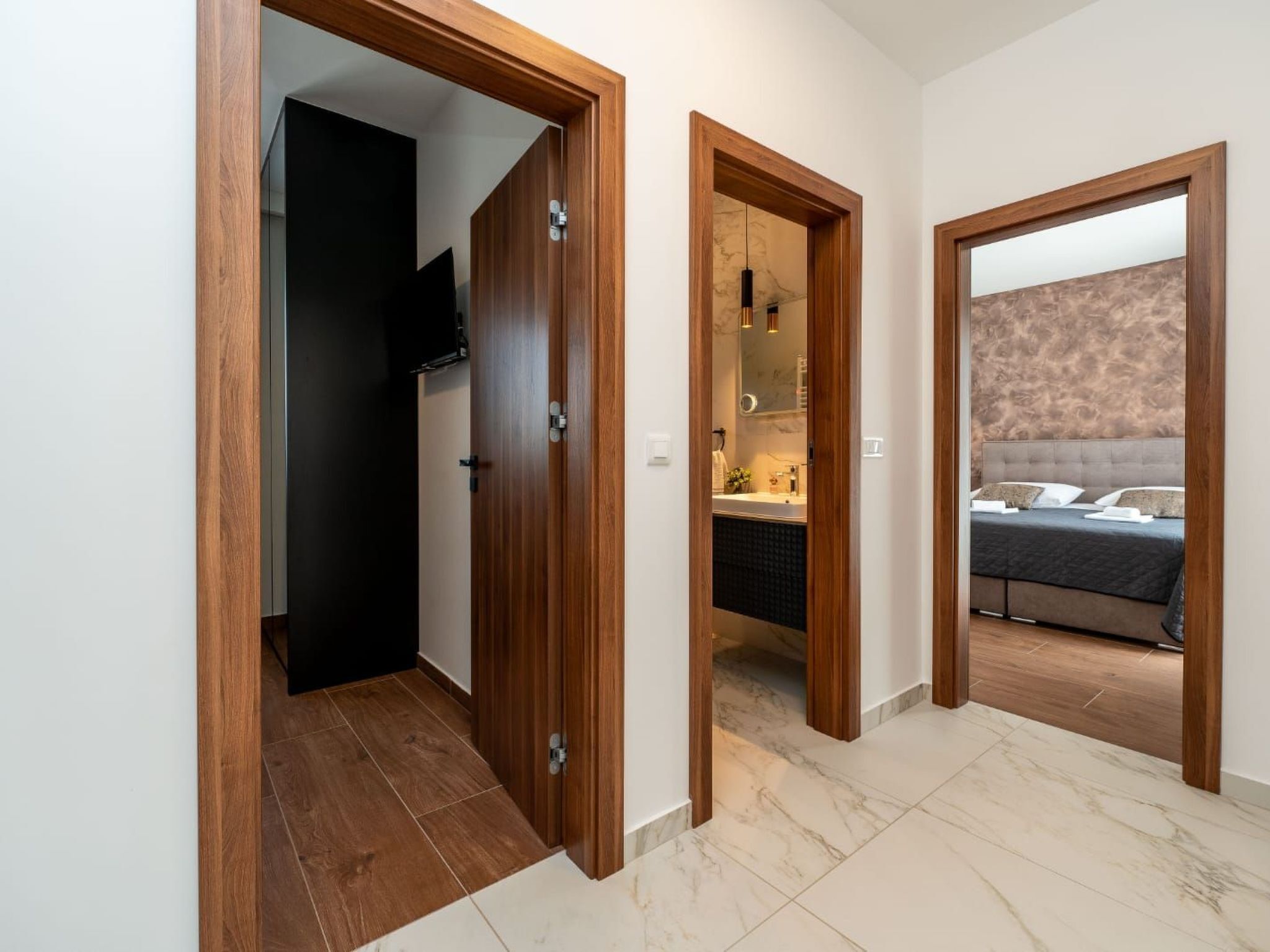 A hallway with wooden doors leading to a bedroom and a bathroom.
