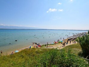 A beach with people swimming and sunbathing, a clear sky, and a distant shoreline. - Wohnung "Mira" direkt am Strand by Interhome (Privlaka)