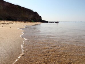 A beach with clear shallow waters, a sandy shore, and a cliff in the background. - Wohnung Barby nahe Sandstrand - Agentur TA Leut by Interhome (Privlaka)