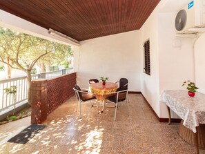 A covered patio with a round table and chairs, a small potted plant, and a brick wall. - Wohnung Barby nahe Sandstrand - Agentur TA Leut by Interhome (Privlaka)