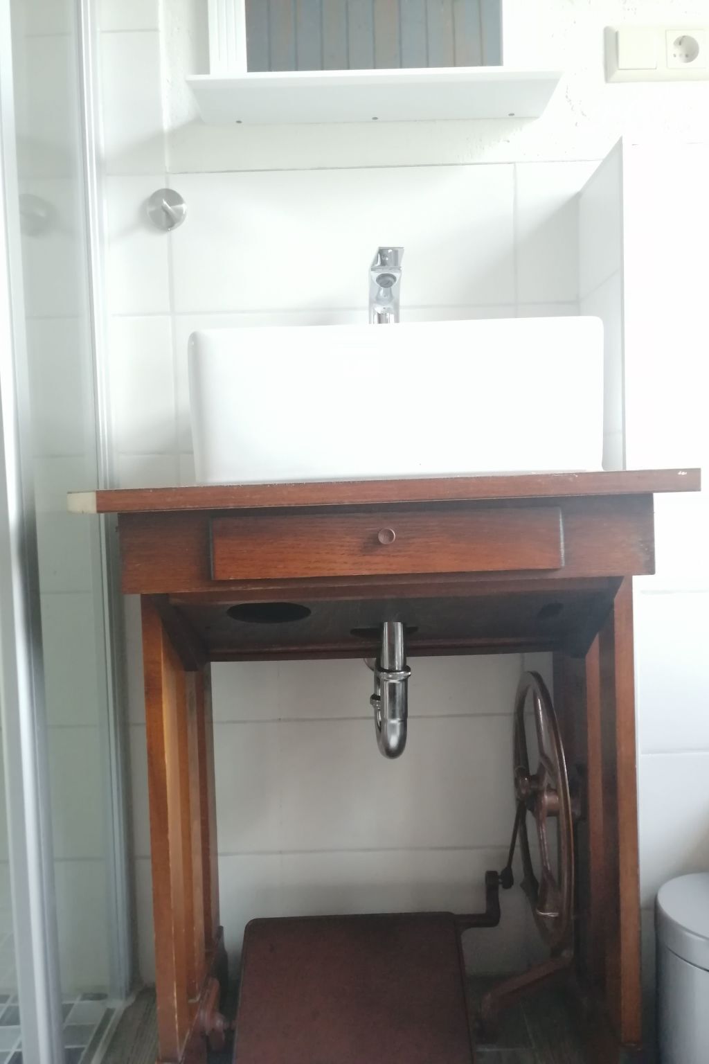 Een badkamer met een witte wastafel, houten wastafelmeubel en een toilet.