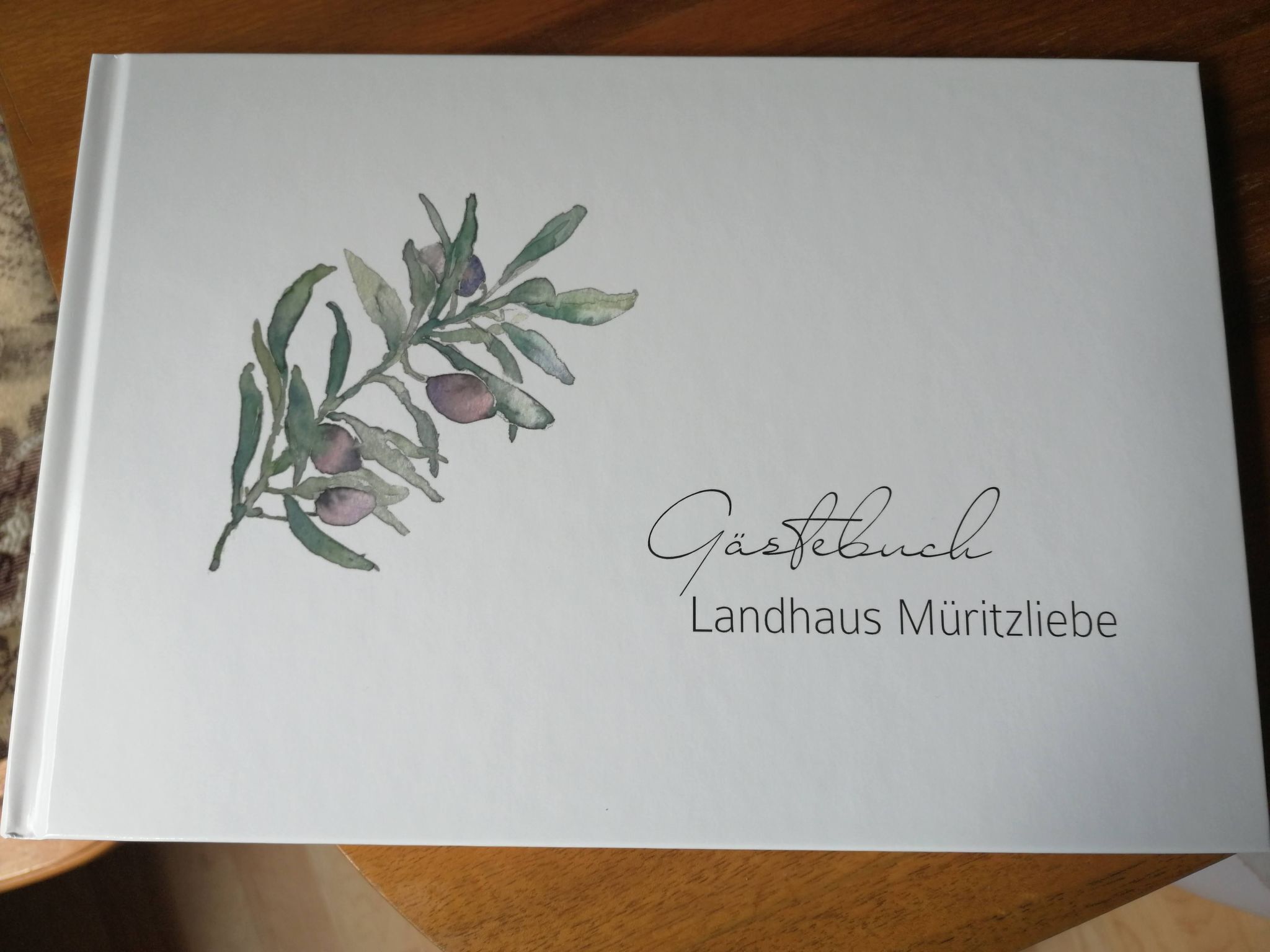 Een boek met de titel 'Gästebuch Landhaus Müritzliebe' en een illustratie van een tak.