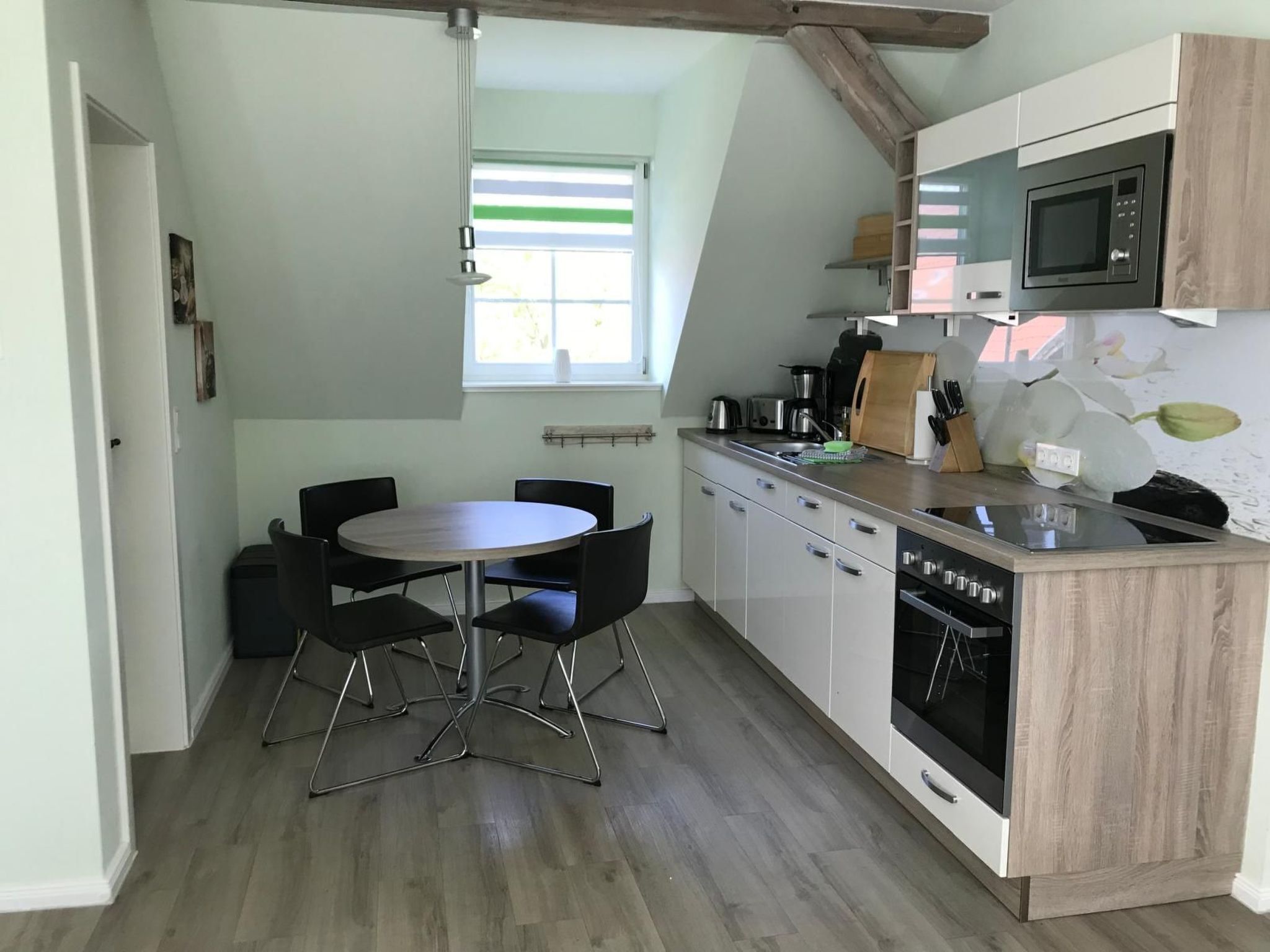 A compact kitchen with a dining table and chairs, a microwave, and a dishwasher.