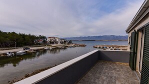 Een balkon met uitzicht op een jachthaven, boten en verafgelegen bergen.