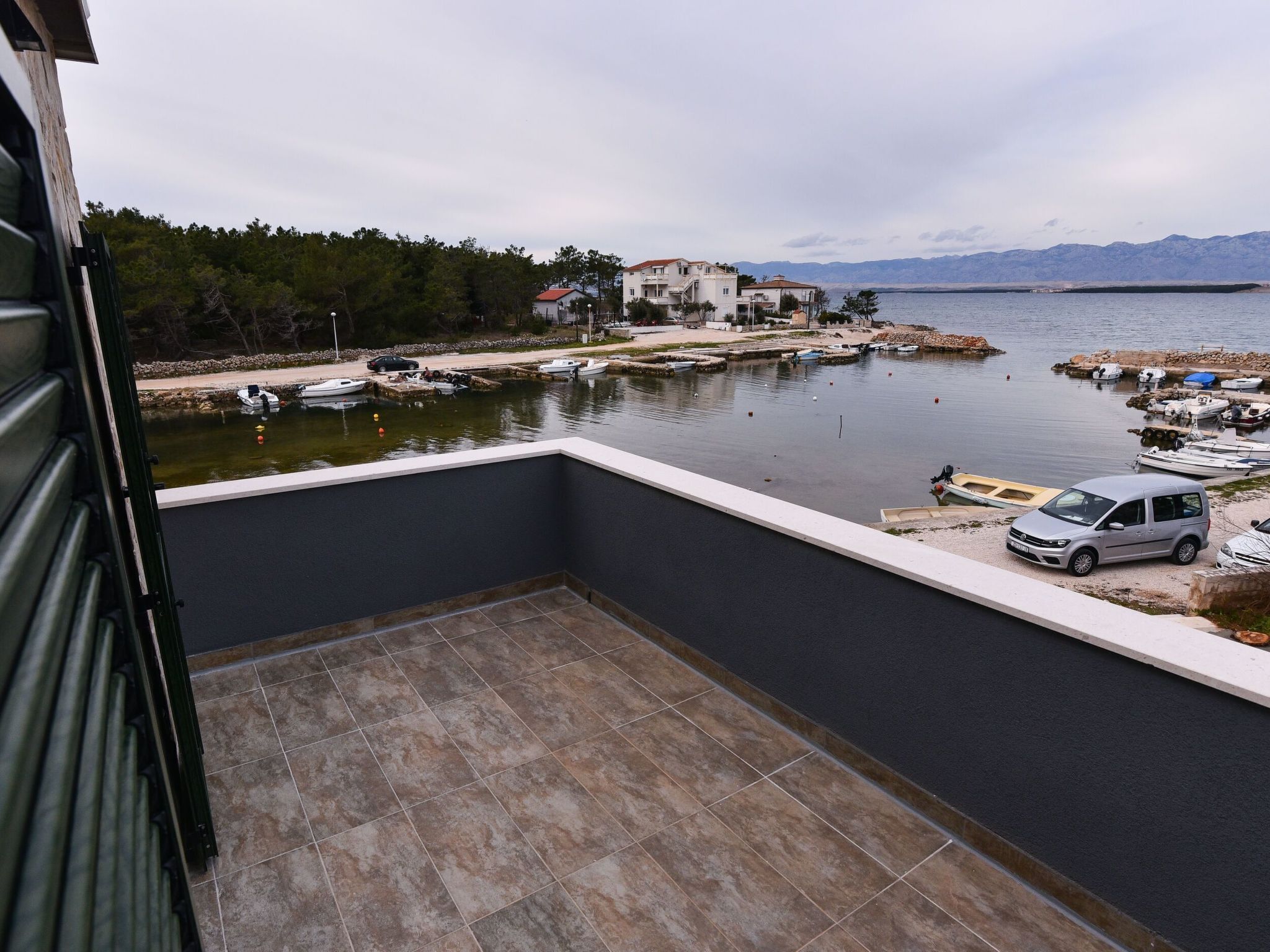 Ein Balkon mit Blick auf eine Marina, Boote und ein entferntes Gebirge.