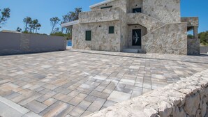 A modern two-story building with a stone facade, a flat roof, and a paved courtyard. - Apartment Sana 3 by Interhome (Vir)