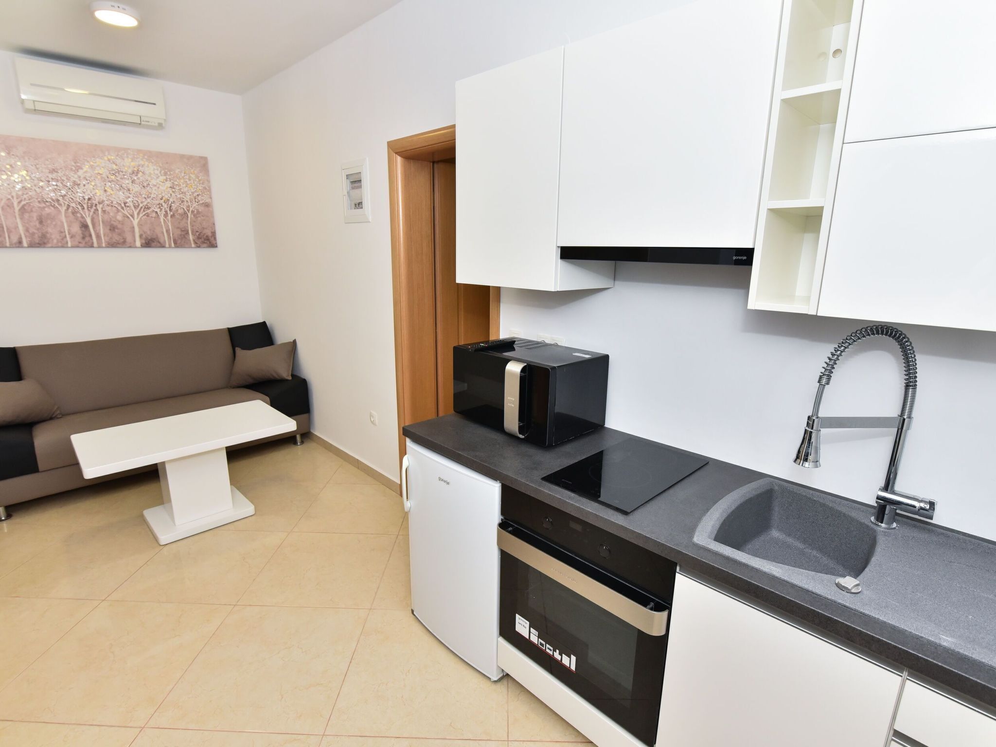 Una cocina moderna con horno empotrado, un lavabo y un lavavajillas compacto.