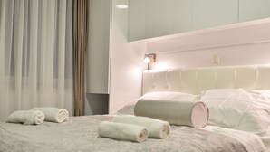 Hotellihuone, jossa on sänky, tyynyt ja sängynpääty.
