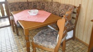 Un tavolo da pranzo in legno con una tovaglia a quadri e una ciotola. Dietro al tavolo, un divano con motivi decorativi.
