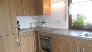 Una cucina con mobili in legno, un fornello e una finestra vista verde.