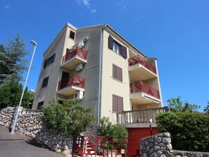 En byggnad med flera våningar, balkonger, en stenmur och en röd port.