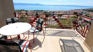 A balcony with a table and chairs, offering a view of a coastal town and the sea. - Apartment für zwei Erwachsene und zwei Kinder by Interhome (Novi Vinodolski)