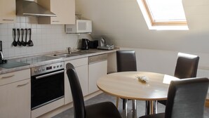 Une cuisine moderne équipée d’un four à micro-ondes, d’une cuisinière et d’un évier. On y trouve une table ronde avec des chaises et une lucarne au-dessus.