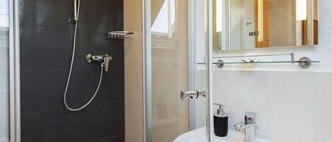 A modern bathroom with a glass-enclosed shower, a white sink, and a large mirror.