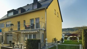 Un bâtiment jaune doté d’un balcon, d’un petit jardin et d’une clôture.