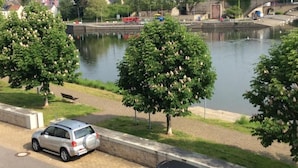 En flod med en bro, træer og en parkeret bil.