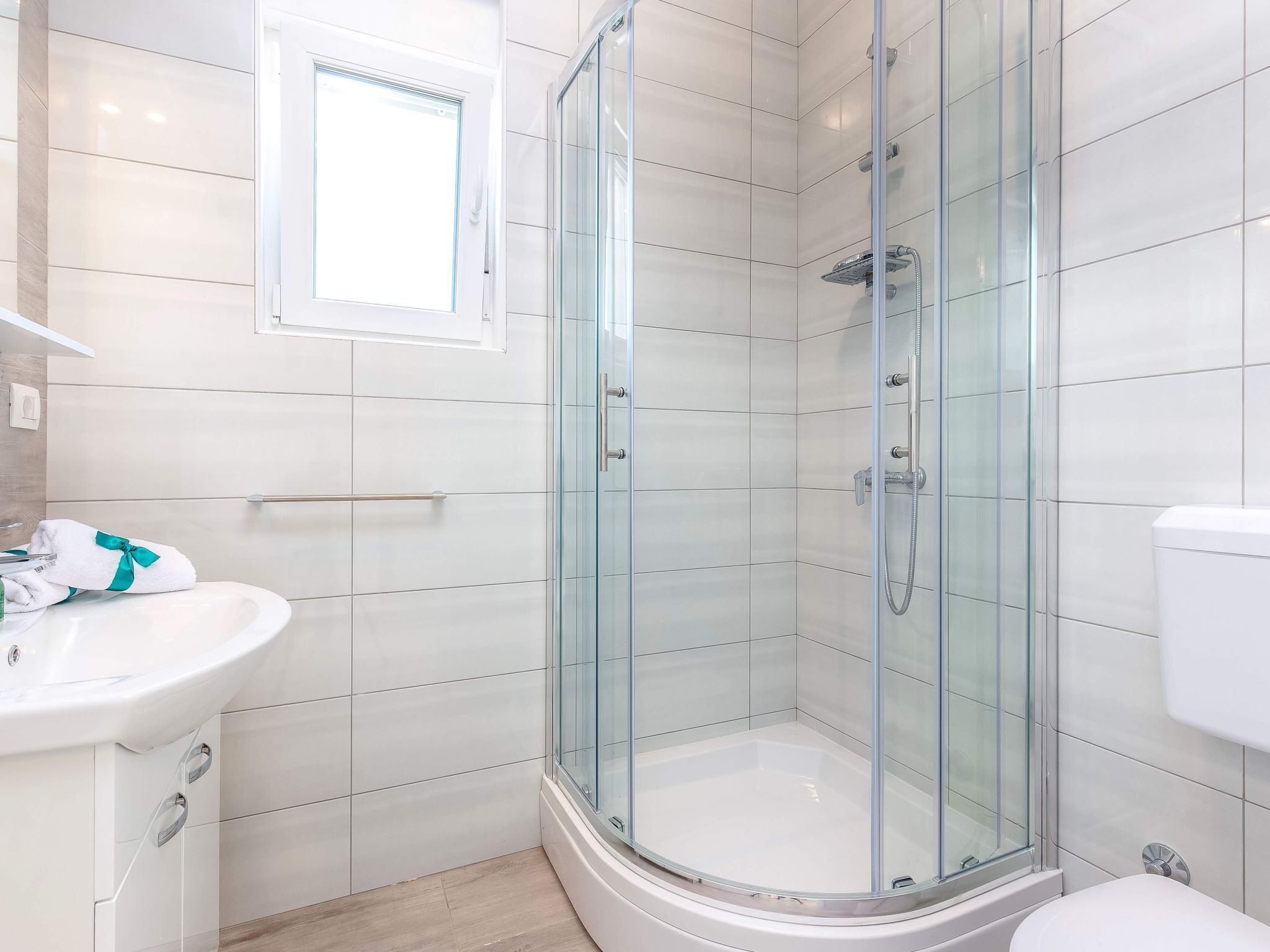 A modern bathroom with a glass-enclosed shower, a white sink, and a toilet.