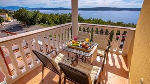 A balcony with a table set for breakfast, overlooking a body of water and greenery.