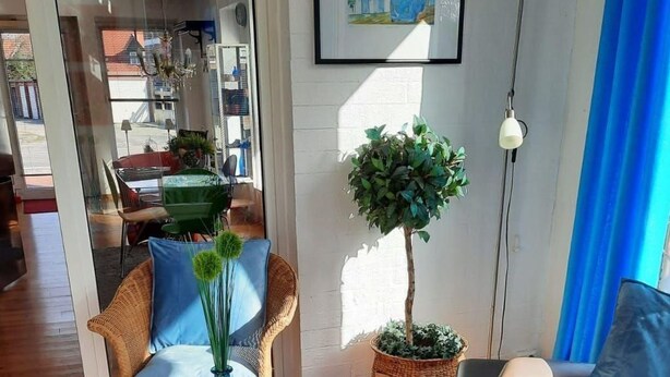 A cozy living area with a wooden coffee table, blue cushions, a potted plant, and a framed artwork on the wall. - Glückstreffer by Interhome (Meppen)